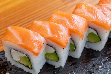 sushi roll filled with avocado, cream cheese and salmon topping
