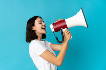 Teenager Ukrainian girl isolated on white background shouting through a megaphone to announce...