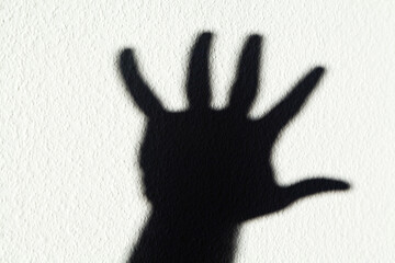 Shadow of a hand against white textured background