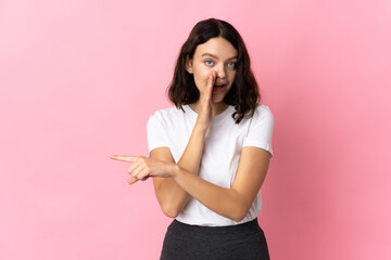 Teenager Ukrainian girl isolated on pink background pointing to the side to present a product and whispering something