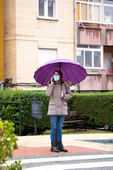 Woman with umbrella talking on the phone in the rain