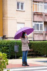 Woman with umbrella talking on the phone in the rain