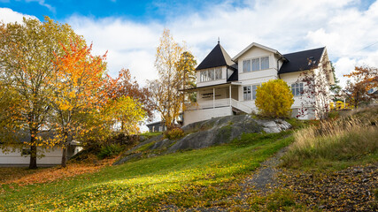 Fototapeta na wymiar Autumn in Scandinavia. Colorful wooden houses, yards, trees. Fall season landscape. Sweden countryside in autumn. View of beautiful European garden design. Golden, yellow, brown, red colors of leaves