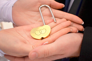 Decorative lock with hearts on the palm of the newlyweds as a symbol of love