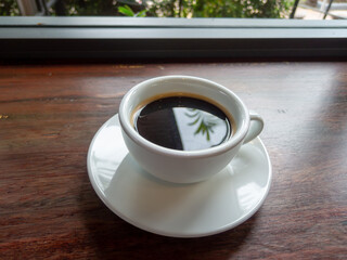 White coffee cup with black coffee placed on the wooden table