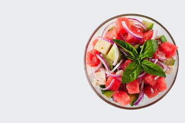 Fresh delicious juicy dietary salad with watermelon, feta cheese, cucumber, red onions and basil leaves in the glass bowl. Close-up. Top view. Healthy food concept.