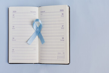 Blue prostate cancer awareness ribbon with a november calendar in the background and copy space.