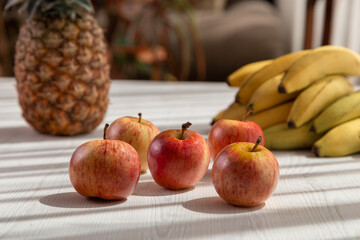 delicious fresh fruits on a white background, shadow and sun, pineapple, apples and bananas, healthy lifestyle, studio design