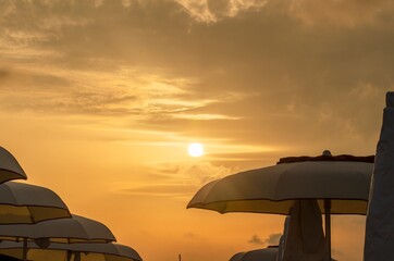 Fototapeta na wymiar Sunset at the beach with beach umbrellas and orange sky