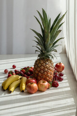 delicious fresh fruits on a white background with sun, pineapple, bananas, apple, strawberry, grapes and bananas, healthy food