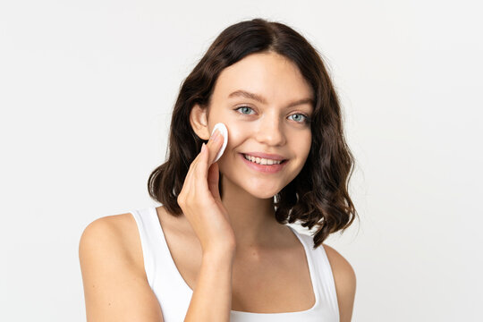 Teenager Ukrainian girl isolated on white background with cotton pad for removing makeup from her face