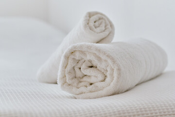 Fototapeta na wymiar Folded white towels on bed, close up view