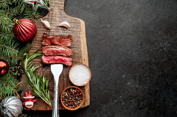 Different degrees of roasting of steak on a meat fork for Christmas on a background of a stone with a spruce and Christmas toys 