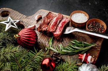 Different degrees of roasting of steak on a meat fork for Christmas on a background of a stone with a spruce and Christmas toys with copy space for your text
