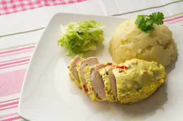 Chicken breast in a sauce with lettuce and potatoes and on a white plate