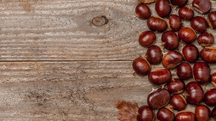 Fresh autumn chestnuts on wooden table, horizontal banner