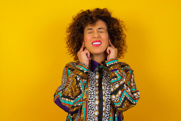 Stop making this annoying sound! Headshot of unhappy stressed out young female making worry face, plugging ears with fingers, irritated with loud noise coming from neighbours who live above her.