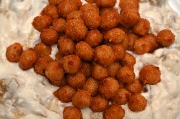 Turkish vegan food. Mini bulghur balls on roasted aubergine mixed with yogurt. Close up and top view.