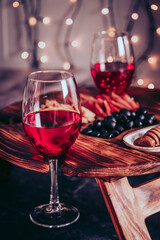  Two glasses of red wine and snacks - olives, meat and cheese on a board. Selective focus, vertical photo