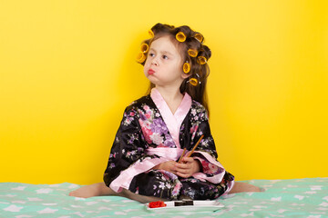 little girl in hair curlers eating sushi on bed
