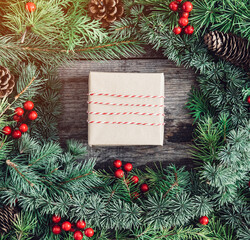 Fototapeta na wymiar Christmas tree branches with gift box on wooden background