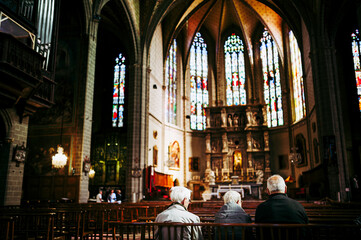 Obraz premium Vue sur l'intérieur d'une cathédrale et des personnes assises sur un banc en train de prier