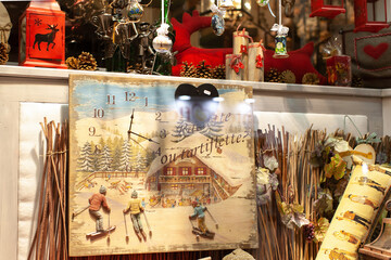 Showcase in a gift shop with Christmas items in the evening. Retro clock with skiers, candle lanterns, pine cones, Christmas decorations. Concept of preparing for holiday, buying gifts for family