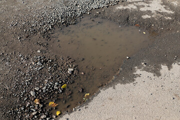 A brown puddle on an old village road, water and asphalt