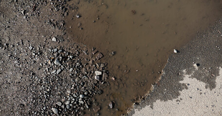 A brown puddle on an old village road, water and asphalt