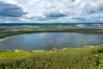 Aerial view of the countryside and a circular lake in the middle of the forest.