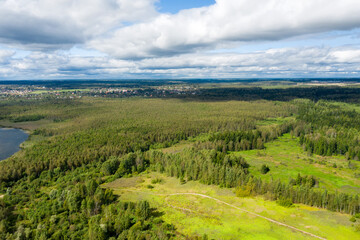 Aerial view of the countryside and a circular lake in the middle of the forest.