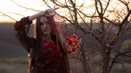 A girl with a dream catcher walks at sunset