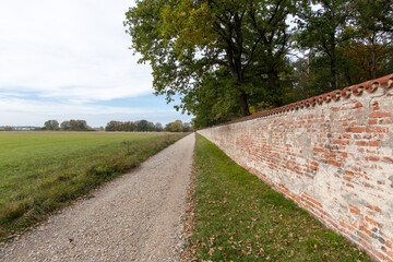 Fototapeta na wymiar alte hohe Backstein Schloss Mauer mit Bäumen