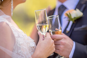 Two glasses of sparkling champagne in hand, a concept for a holiday, bokeh, in a restaurant or outdoors. Women's and men's hands hold champagne glasses.