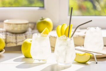 Summer cocktail with green apple and ice on the white table near window in the sunny summertime. Selective focus image with copy space