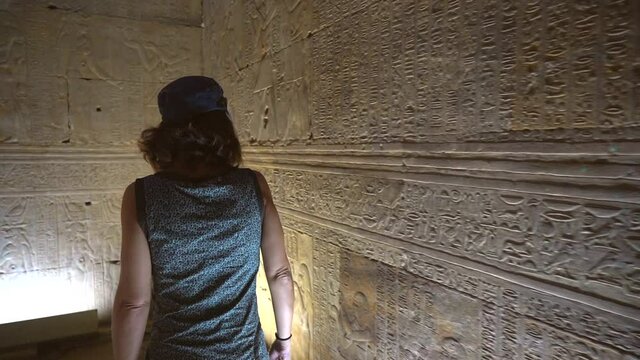 A young woman looking at the Egyptian drawings inside the Edfu Temple. Egypt. River Nile in the city of Edfu near Aswan, Greco-Roman construction, dedicated to Horus