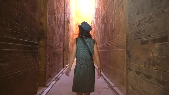 A young woman visiting the interior of the Edfu Temple near the city of Aswan. Egypt. Plane following from behind. Nile River in the city of Edfu, Greco-Roman construction, dedicated to Horus