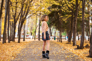 Portrait of a young beautiful girl in beige sweater and black skirt