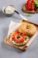 Bagel with cream cheese and smoked salmon. Breakfast sandwich on gray background.