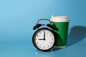 Morning alarm clock and disposable bright positive green paper cup