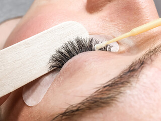 Close-up of the eyelash extension removal procedure. Portrait of a woman in a beauty salon