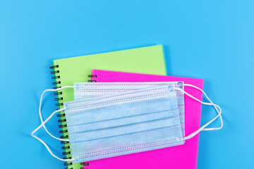Two spiral notebooks and medical protective masks on top. New normal - concept.