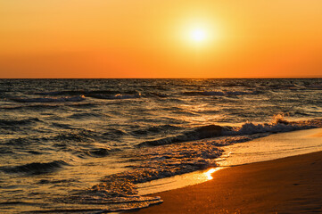 Beautiful orange sunset over the Black Sea. Evening sea with waves. Focusing in the center of the frame.