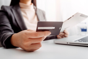 businesswoman hand using smart phone, tablet payments and holding credit card online shopping, omni channel, digital tablet docking keyboard computer at office in sun light