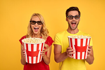 Joyful young couple two friends guy girl in 3d glasses isolated on yellow background. People in...