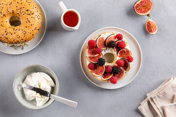 Bagel with cream cheese, figs, raspberries, blackberries and honey.  Gourmet sandwich on gray...