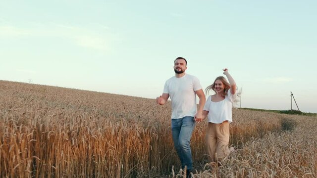 Man and woman on romantic date. Loving couple is walking through wheat field . Sunset. Love relationship, slow motion.