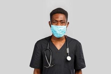 Confident male doctor. Cheerful african doctor in medical mask standing against gray background