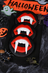 Vampire fangs protruding from scarlet lips, Glazed honey gingerbread cookies. Halloween food idea