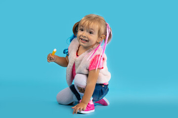 Little girl plays on the floor and eats sweets. Photo on a blue background. Holiday concept,...